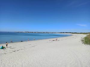 a group of people on a beach near the water at Gite Terre Mer Des Sables Blancs in Plobannalec-Lesconil