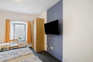 a bedroom with a bed and a tv on a wall at Pension Mosellablick in Briedern +25 photos