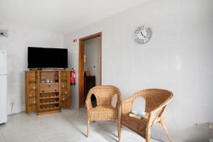 a living room with two chairs and a clock on the wall at Bouros's Cliff in Serra do Bouro