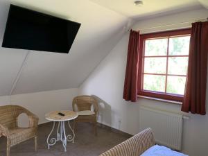 a room with a tv and a table and chairs at Sabines Badehaus mit Innenpool in Steinkoppel