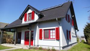 a house with red shutters and a black roof at Sabines Badehaus mit Innenpool in Steinkoppel