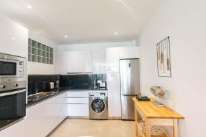 a kitchen with white cabinets and a washer and dryer at Modern Apartment in Cómpeta I in Cómpeta