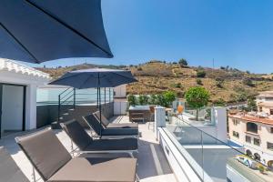 a patio with chairs and an umbrella on a balcony at Modern Apartment in Cómpeta I in Cómpeta