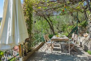 ein Tisch, Stühle und ein Sonnenschirm auf einer Terrasse in der Unterkunft Tavernetta in campagna in Zoagli