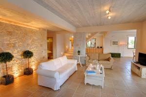 a living room with white furniture and a stone wall at Villa Nautilos Ideales Resort in Kefallonia