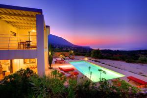 a villa with a swimming pool at sunset at Villa Nautilos Ideales Resort in Kefallonia