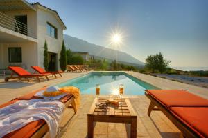 a swimming pool with a table next to a house at Villa Nautilos Ideales Resort in Kefallonia