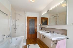 a bathroom with two sinks and a tub and a mirror at Ferienhaus Christine Bodensee Nord in Pfullendorf +16 photos