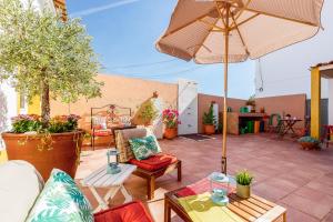a patio with an umbrella and chairs and tables at Sossego Alentejano in Reguengos de Monsaraz