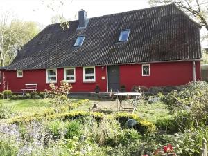 ein rotes Haus mit einem Garten davor in der Unterkunft Room 24 in Behrendorf