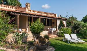 a house with two white chairs in the yard at Villa Lucia in Costa Rei