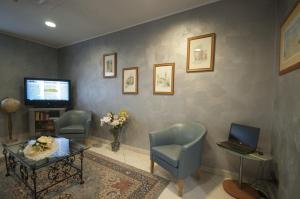 Ein Wartezimmer mit Stühlen, einem Tisch und einem Fernseher in der Unterkunft Hotel Brindor in Poirino