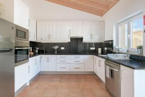 a kitchen with white cabinets and black counter tops at Paraiso da Serva - Flor do Rosto 1 in Odemira