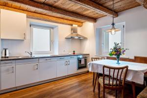 eine Küche mit weißen Schränken und einem Tisch mit Stühlen in der Unterkunft Grotthof in Deutschnofen