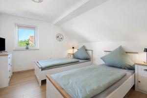 two beds in a white room with a window at Ferienhaus Donauliebe in Vohburg an der Donau