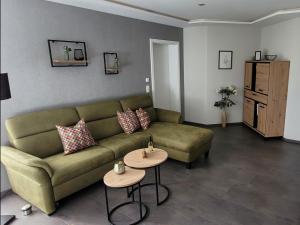 a living room with a green couch and two tables at Schmallenberger Auszeit in Schmallenberg