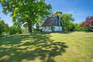 a small white house with a tree in a field at Ferienhaus Kitzklause in Walkendorf