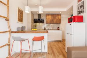 a kitchen with a white refrigerator and two bar stools at Fada Lloret in Lloret de Mar