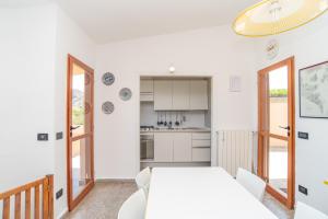a white kitchen with a white table and chairs at House Punta Nera in Palau