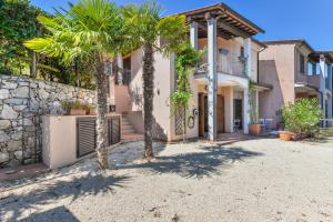 a house with palm trees in front of it at Appartamento Thomas in Capoliveri