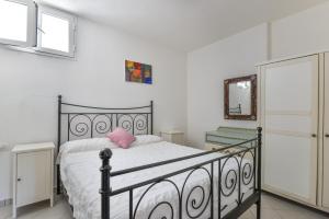 a bedroom with a bed with a pink pillow on it at Appartamento Thomas in Capoliveri