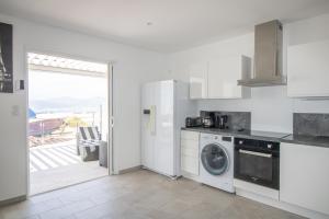 a white kitchen with a washer and dryer in it at Splendide Grand Appart Neuf in Albitreccia