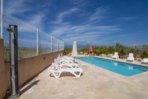 a swimming pool with white lounge chairs and a fence at Splendide Grand Appart Neuf in Albitreccia