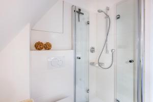 a white bathroom with a shower with a glass door at Inselliebe in Pellworm +19 photos