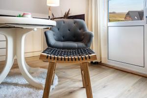 a blue chair with a wooden stool in a room at Inselliebe in Pellworm