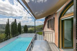 a house with a balcony with a swimming pool at Villa Cristina in Riparbella
