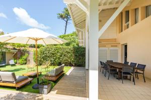 a patio with an umbrella and a table and chairs at Dune Lodge 1- Capbreton Hossegor - in Capbreton