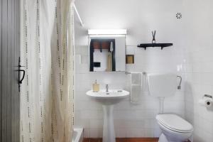 a white bathroom with a toilet and a sink at Pedras Del Rei 8 in São Pedro +10 photos