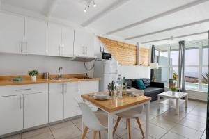a kitchen with white cabinets and a table with chairs at Loft Amanecer in Mácher