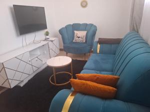 a living room with a blue couch and two chairs at Bright Homes in Eldoret