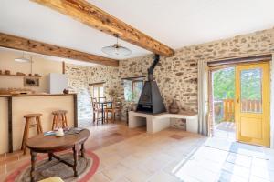 a living room with a stone wall and a table at Mas Vizern avec bain nordique in Taillet