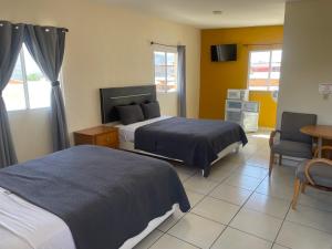 a hotel room with two beds and a chair at Hotel Ranchito in Ensenada