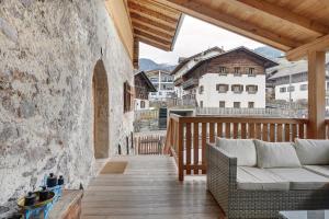 a wooden porch with a couch and a table at Alpin Chalet Samer Apt Bauernstube in Sarntal