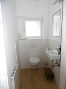 a white bathroom with a toilet and a sink at Schlößleweg 2a in Bodman-Ludwigshafen +21 photos