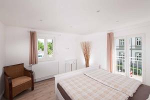 a bedroom with a bed and a chair and windows at Haus Behr am See in Radolfzell am Bodensee