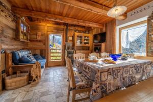 a dining room with a table and a couch at Baita Mas Sternai Nel Parco in Bagni di Rabbi