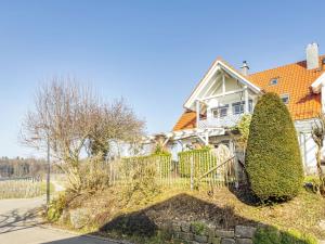 a white house with a fence and trees at Ferienwohnung Meckenbeuren in Meckenbeuren