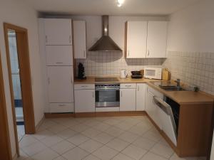 a kitchen with white cabinets and a stove top oven at Ferienwohnung Mössingen in Mössingen