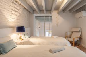 a white bedroom with two beds and a chair at Orbyz in Seville