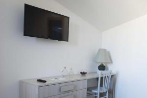 TV en la pared con escritorio y silla en B&B Solimo, en Sulmona