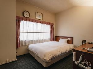 a bedroom with a bed and a window with a clock at Hotel Union in Kagoshima