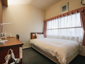 a bedroom with a bed and a window at Hotel Union in Kagoshima