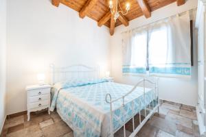 a white bedroom with a bed and a window at Villa Tramonto in Villasimius