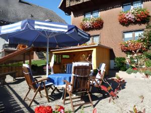 a table and chairs under an umbrella in front of a building at Rathäusle in Titisee-Neustadt