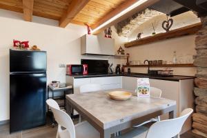 a kitchen with a table and a black refrigerator at Chez Margot Et Sophie in Torgnon