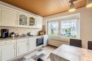 a kitchen with white cabinets and a table and a window at Familie Heiko Schroth in Neußen